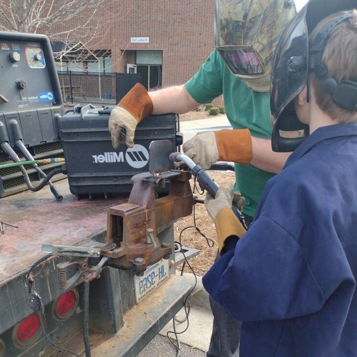 买球 welding instructor shows a Boy Scout how to handle welding equipment safely